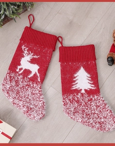 Detail view of red knitted Christmas stockings with white reindeer and tree patterns