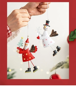 Hand holding painted metal gnome and snowman Christmas ornaments with hanging strings