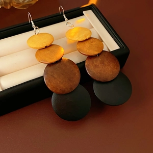 Detail of bohemian tiered wooden disc drop earrings with gradient brown tones in a jewelry box