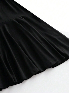 Black off-shoulder dress with a high waist and textured knit fabric hemline close-up