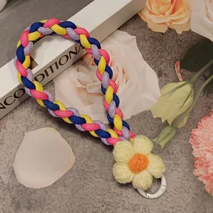 Close-up of a handmade four-color braided phone lanyard with a knitted yellow flower detail