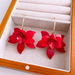 Détail de boucles d'oreilles fleurs en résine rouge dans un écrin à bijoux en lin beige