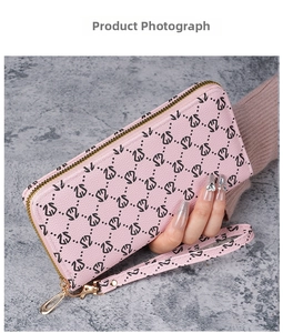 Portefeuille long rose avec motif cygne et dragonne en cuir montré en gros plan
