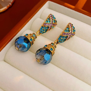 Macro shot of vintage floral earrings with blue crystal and purple stones in a beige box