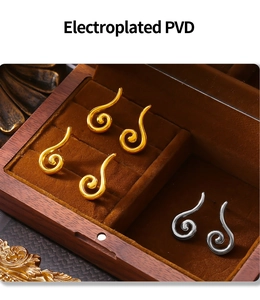 Close-up of PVD plated spiral earrings in gold and silver finish on a wooden jewelry tray