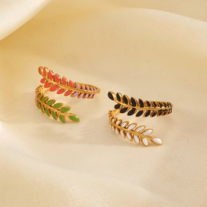 Fashionable gold leaf rings with colorful enamel on soft beige silk background