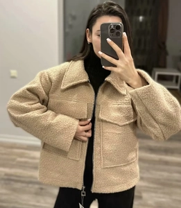 Detail of beige teddy fleece jacket featuring lapel collar and large front pockets