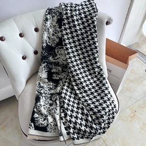 Detail of soft black and white houndstooth scarf with abstract ink pattern on a white chair