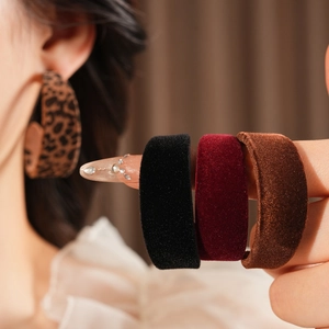 Close-up of velvet C-shaped earrings in leopard print, black, burgundy, and brown colors