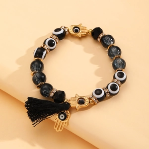 Detail van kralenarmband met Hamsa-bedels, boze oog kralen en zwart zijden kwastje