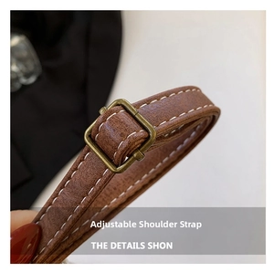 Macro shot of adjustable brown leather shoulder strap with vintage bronze buckle and white stitching