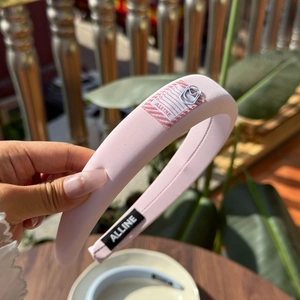 Detailed macro view of pink padded headband with striped tag and silver paperclip