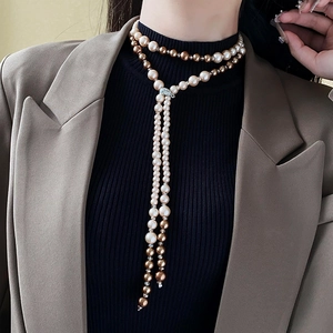 Detailed view of long tassel necklace with white and champagne pearls on professional model