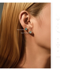 Close-up of blue 5mm and 6mm round firework cut silver stud earrings on a model ear