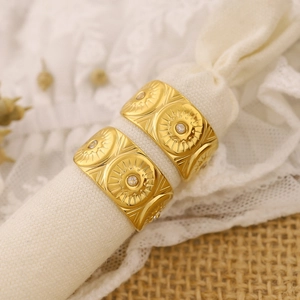 Macro detail of golden sunflower rings with clear gemstones on textured fabric