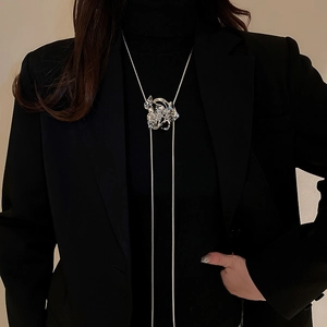 Detail of silver liquid metal flower pendant on a long snake chain over dark clothing