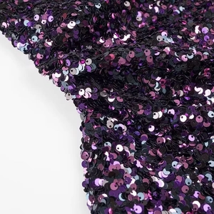 Close-up macro view of vibrant purple sequins on a shimmering party dress fabric