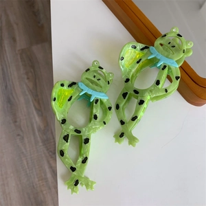 Detail von grünen Frosch-Haarklammern mit Leopardenmuster und blauer Schleife aus Acetat