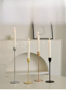Detail of four slender metal candle holders in gold, silver, rose gold, and black finishes