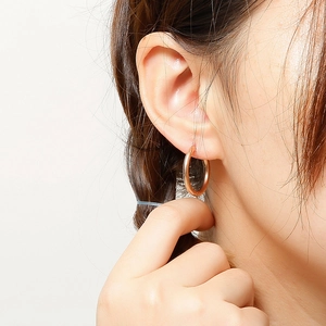 Close-up of a minimalist rose gold polished hoop earring worn on a model ear