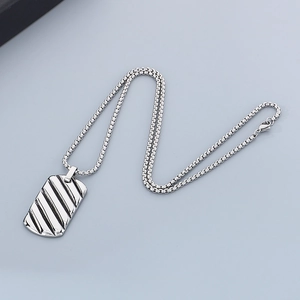 Macro detail of silver stainless steel rectangular pendant with diagonal wavy textures