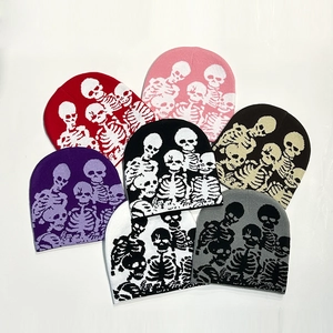 Multiple colorful knitted beanies featuring Halloween skull patterns on white background