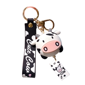 Cute cartoon cow keychain with black PVC strap and golden clasp on white background