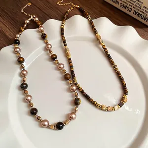 Vintage tiger eye and pearl beaded necklace set in elegant ceramic dish on wood table