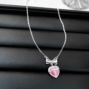 Close-up of pink heart-shaped opal pendant with zircon bow on a fine silver chain