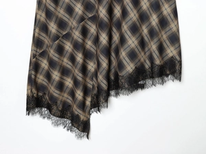 Détail de l'ourlet de jupe écossaise asymétrique avec bordure en dentelle noire délicate