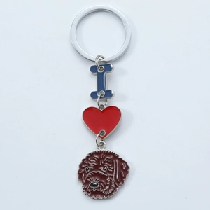 Detail view of metal keychain with blue letter I, red heart, and brown dog pendant