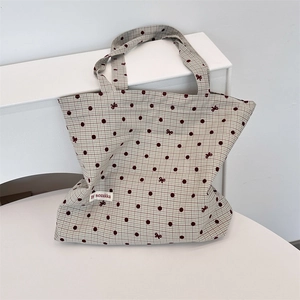 Detail shot of canvas tote bag with polka dots and bow print on a minimalist pedestal