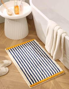 Close-up of blue and white striped absorbent bath mat with soft yellow plush edges