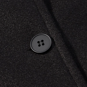 Close-up of the black tweed fabric texture and matching resin button on the short jacket