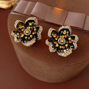 Vintage flower earrings with crystals and colorful stones on a brown velvet background