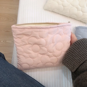 Detail of soft pink quilted cosmetic bag with floral embroidery and puffy texture