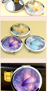 Close-up of circular metal makeup mirrors with colorful butterfly designs in silver frames