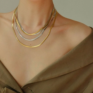 Close-up of model wearing layered gold and silver snake chains with metallic luster