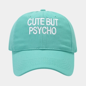 Detail of mint green cotton baseball cap featuring white CUTE BUT PSYCHO embroidery