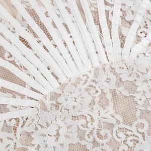 Detailed macro view of white floral lace fabric with lustrous satin ribbon trim