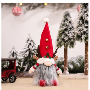 Close-up of a Christmas gnome with reindeer antlers, bells and festive holly decorations