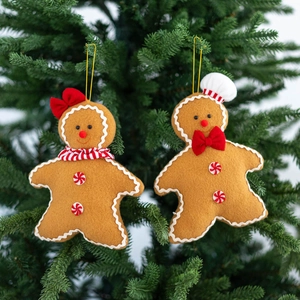 Detail of felt gingerbread man ornaments with chef hat and bow hanging on a green tree