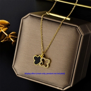 Detail of a thin gold chain on a jewelry box with clover pendants and metal edging