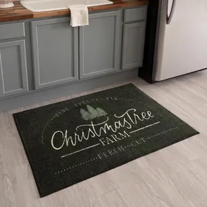 Detailed view of dark grey Christmas mat with pine tree design on light wood floor