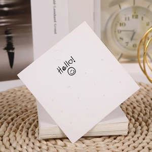 Close-up of square white jewelry display cards with earring holes and hello smiley face