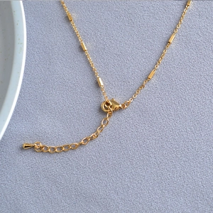 Detail of gold-plated brass necklace with lobster clasp, extender chain and square beads