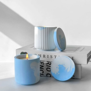 Chic candle set with white ribbed and blue marble jars on books with soft shadows