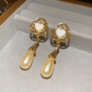 Macro detail of vintage gold heart earrings with mother of pearl and teardrop pearls