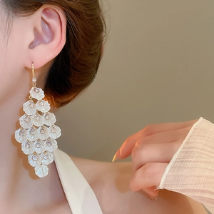 Detail of elegant white petal tassel earrings with sparkling crystals and gold hooks