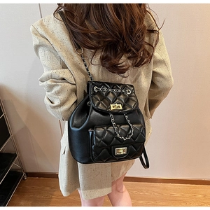 Close-up of black quilted leather backpack featuring gold twist lock and chain strap